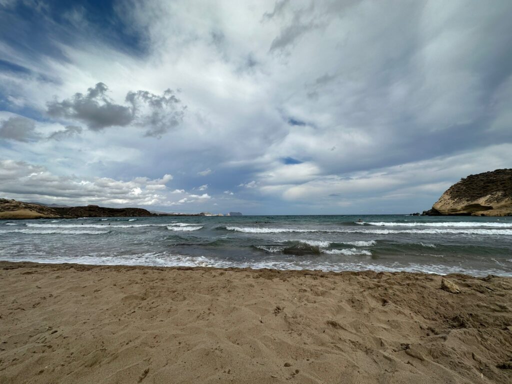 Wolken und grauer Himmel am Meer mit Strand und Felsen